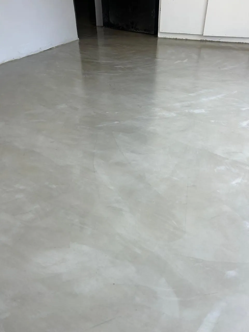 Empty bedroom with a pale grey epoxy floor with a soft metallic sheen